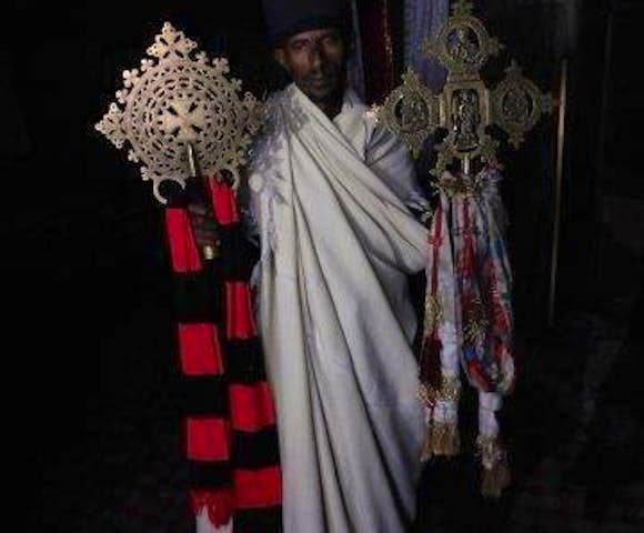 Priest holding ancient artefacts inside rock-hewn churches of Lalibela in Ethiopia