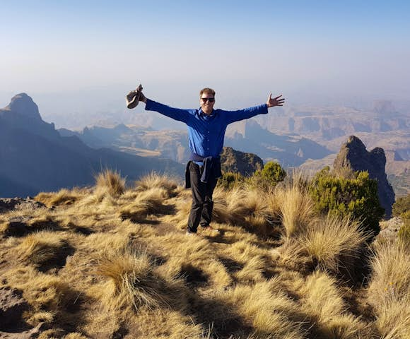 Man spreading arms in front of landscape view in the Simien Mountains