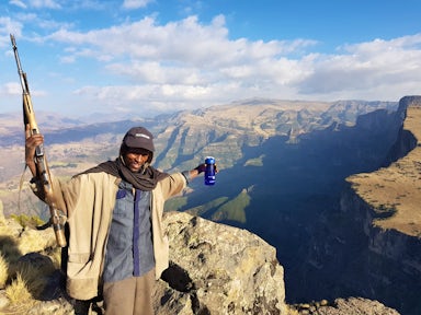 Scout with rifle spreading arms in front of landscape in the Simien Mountains